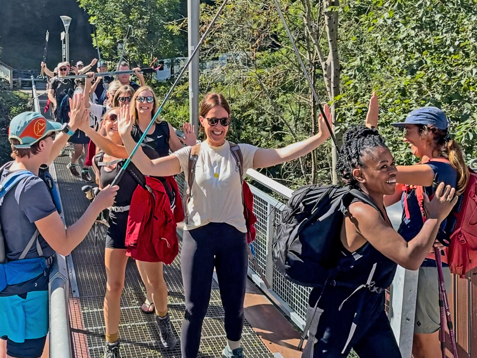 A group of hikers celebrating crossing a bridge at the end of an hiking adventure