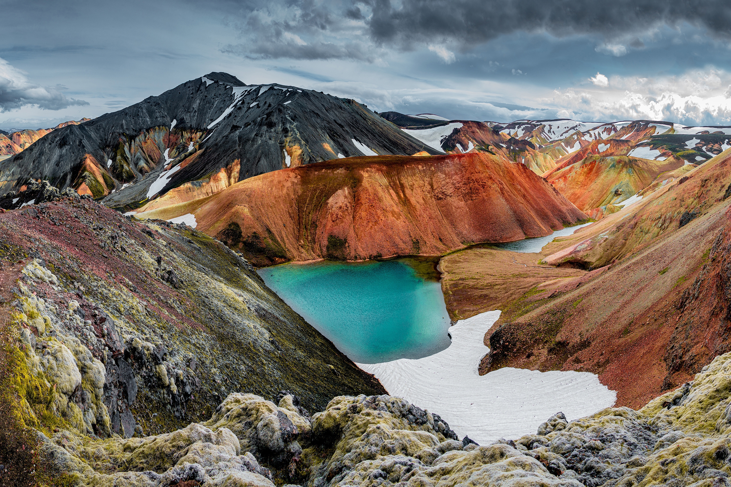 Landscape view of colorful rainbow volcanic Landmannalaugar mountains and famous Laugavegur hiking trail, with dramatic sky and snow in Iceland